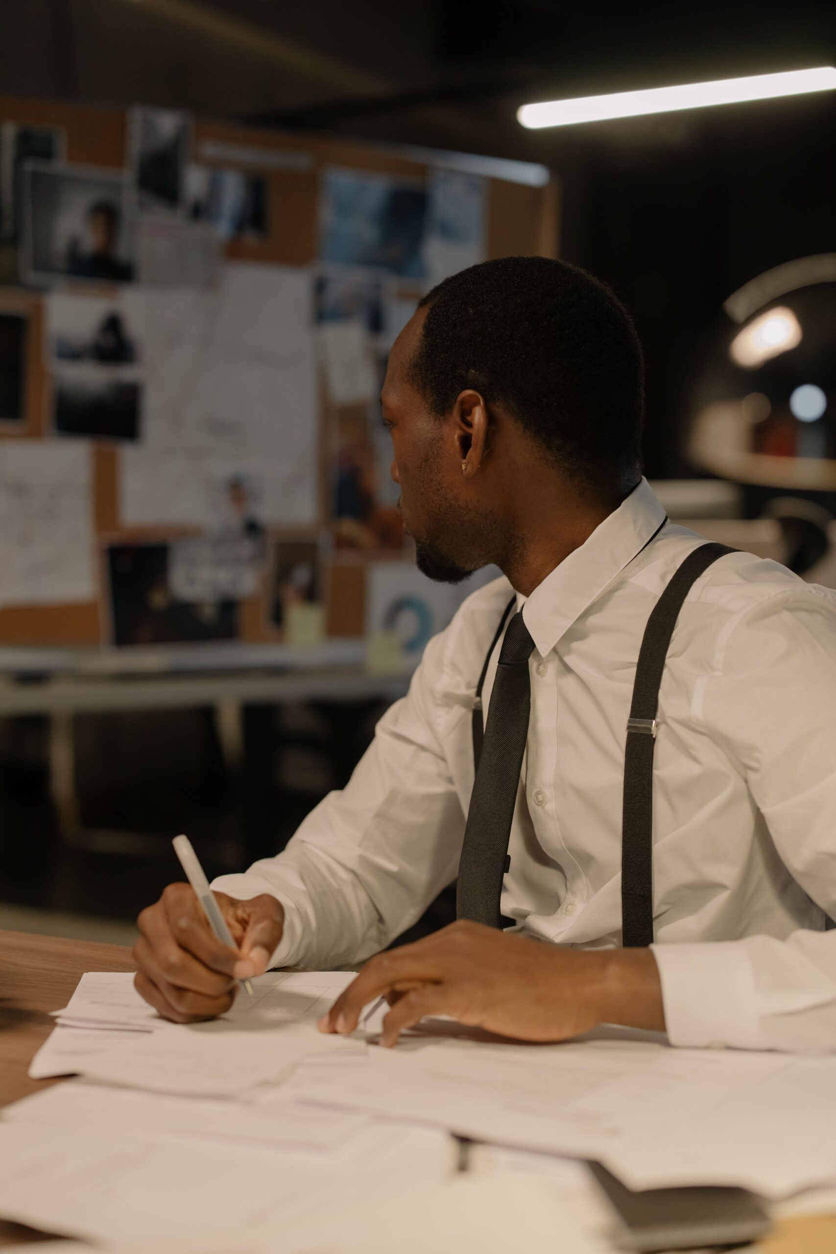 Home A detective focusing on evidence in a dimly lit office, creating a mysterious atmosphere.